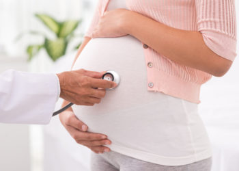 Cropped image of doctor checking pregnant woman with stethoscope